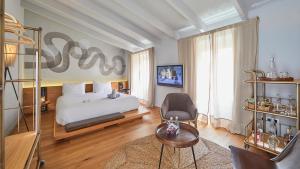 a bedroom with a bed and a chair and a tv at Purohotel Palma in Palma de Mallorca
