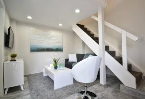 a living room with a white chair and stairs at Modern Loft wQueen Loft Steps to Beach in Hollywood