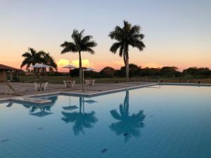 a pool with palm trees and a sunset in the background at Carlos Franco Country Golf in Arroyos y Esteros