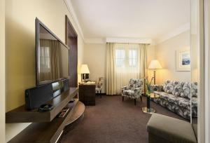 a living room with a television and a couch at Grand Hotel Bohemia in Prague