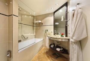 a bathroom with a tub, sink and mirror at Grand Hotel Bohemia in Prague