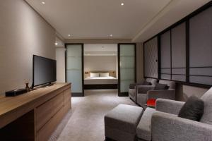 a living room with a television and a bed at Royal Inn Taipei Nanxi - MRT Zhongshan Station in Taipei