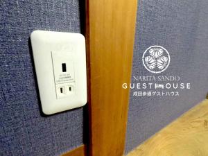 a switch on a wall with a sign on it at Narita Sando Guesthouse in Narita