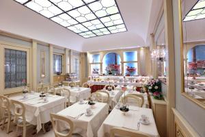 un restaurant avec des tables blanches, des chaises et des fenêtres dans l'établissement Hotel Colombina, à Venise