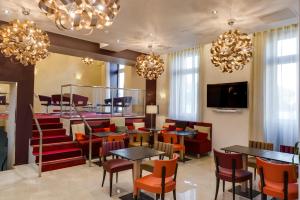 a restaurant with tables and chairs and chandeliers at Hôtel Le Châteaubriant in Châteaubriant