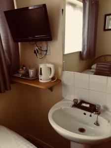 a bathroom with a sink and a tv on the wall at Alder Lodge in Cambridge