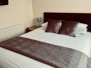 1 dormitorio con cama blanca y almohadas marrones en Alder Lodge en Cambridge