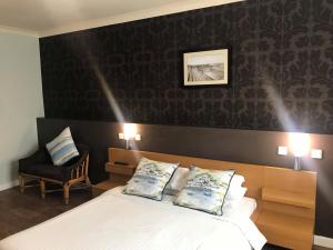 a bedroom with a white bed and a chair at The Anchor Hotel & Bars in Ingoldmells