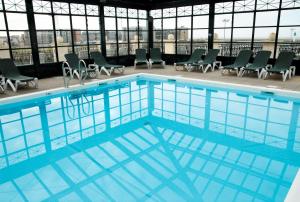 ein großer Pool in einem Gebäude mit Stühlen in der Unterkunft SOWELL RESIDENCES Le Port in Trouville-sur-Mer