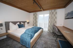 1 dormitorio con 1 cama grande con manta azul en Frühstückspension Jagdhof, en Obertilliach