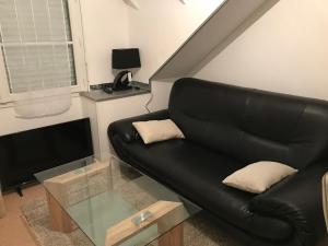 - un canapé en cuir noir dans le salon avec une télévision dans l'établissement Appartement Rue Victor Hugo - Port de la Houle, à Cancale