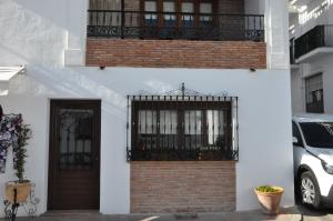 a white building with a balcony and a door at La Casita De Angela in Frigiliana