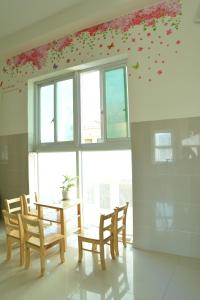 une salle à manger avec une table, des chaises et des fleurs sur le mur dans l'établissement Hoang Chau Motel, à Vung Tau