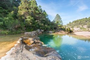 a pool of water next to a beach with trees at Casa El Mirador in Beceite