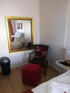 een slaapkamer met een spiegel, een stoel en een bed bij Lighthouse Accommodation in East London