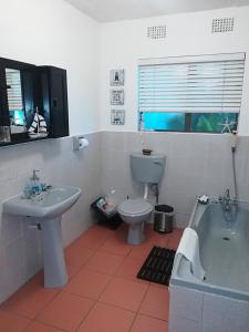 a bathroom with a sink and a toilet and a tub at Lighthouse Accommodation in East London