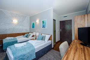 a hotel room with two beds and a flat screen tv at Hotel Active in Szczecinek