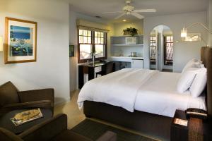 a bedroom with a large white bed and a kitchen at Casa Del Mar Inn in Santa Barbara