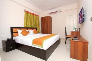 Dormitorio con cama, escritorio y TV en Arra Suites kempegowda Airport Hotel, en Devanhalli
