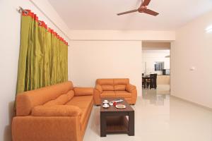a living room with two orange couches and a table at Arra Suites kempegowda Airport Hotel in Devanhalli