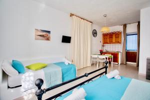 a bedroom with two beds and a kitchen with a table at Il Veliero Blu Lipari Centro - Guest House in Lipari