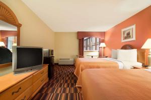 a hotel room with two beds and a flat screen tv at Travelodge by Wyndham Sturgis in Sturgis