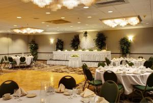 un salón de banquetes con mesas y sillas blancas en Wyndham Garden Philadelphia Airport, en Essington