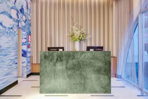 a lobby with a green counter with a vase of flowers at Wyndham Garden Brooklyn Sunset Park in Brooklyn