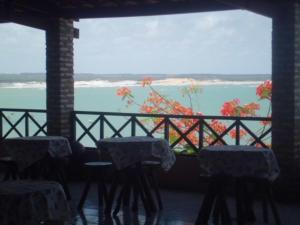 a room with tables and chairs and a view of the ocean at Pousada Ecobaia in Baía Formosa