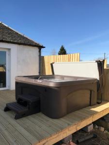 uma banheira de hidromassagem no topo de um deque em Carriage Cottage Hot Tub em Beith