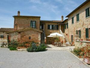 a large brick building with a patio with an umbrella at Gorgeous Cottage in Asciano with Swimming Pool in Asciano