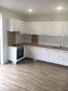 デブレツェンにあるCity Gardens Apartmanok Debrecen 1.の白いキャビネット付きのウッドフロアのキッチン