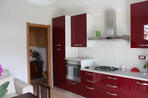 a kitchen with red cabinets and a stove top oven at Mary Casa Vacanza in Monterotondo