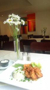 a plate of food on a table with a vase of flowers at Hotel Hex Estelí in Estelí +17 photos