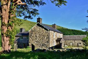 an old stone building with a hill in the background at The Firecat Country House Guesthouse in Mallwyd +8 photos