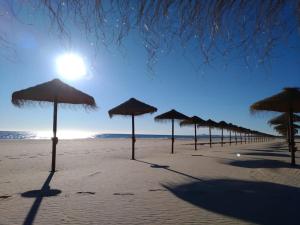 a row of straw umbrellas on a beach at Casa Verão Azul in Monte Gordo