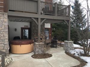 a house with a deck and a hot tub at Boyne Mountain Creekside Condo in Boyne Falls