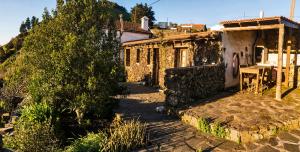 uma casa de pedra com uma árvore em frente em Geranios Rojos II em Las Rosas