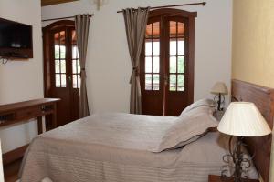a bedroom with a bed and two windows at Hospedaria de Alice in Tiradentes