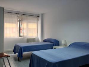 - une chambre avec 2 lits avec des draps bleus et une fenêtre dans l'établissement Loft en Torrelavega, à Torrelavega