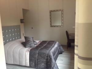 Dormitorio con cama con manta gris y espejo en Auberge De L'Abbaye, en Hambye