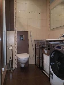 a bathroom with a toilet and a washing machine at Helen Apartment in Riga