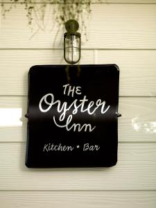 a sign that reads the ownerim kitchen bar hanging on a door at The Oyster Inn in Oneroa