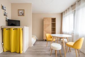 a living room with a table and yellow chairs at Appartement Lyon Gerland - Enjoy in Lyon in Lyon