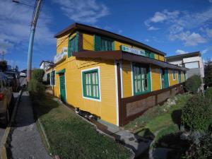 una casa amarilla con ventanas coloridas en una calle en Amanecer de la Bahía en Ushuaia