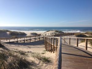 a wooden path to the beach with the ocean in the background at Apart. Dunas da Torreira in Torreira