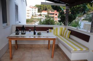 a table and a bench on a balcony with a window at Villa Delfin in Sutivan