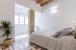 a white bedroom with a bed and a potted plant at Casa Nolla in Valencia