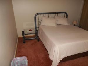 a bedroom with a bed and a night stand next to it at Pilot Inn Accommodation in Kempton Park