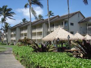 a resort building with umbrellas and palm trees at Islander on the Beach Unit 244 in Kapaa